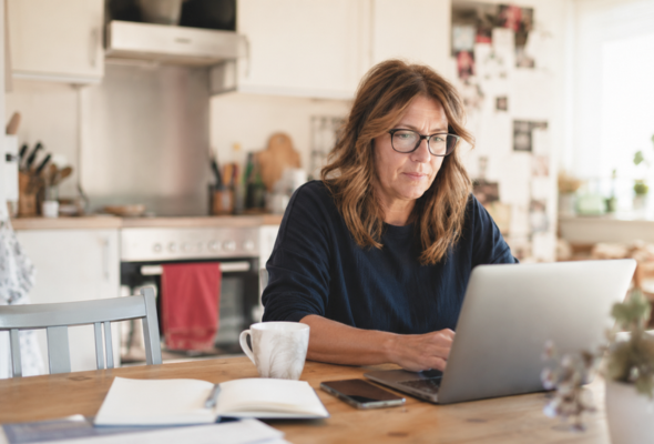 Frau arbeitet konzentriert am Laptop in ihrer Küche – Business aufbauen mit Job im echten Alltag.